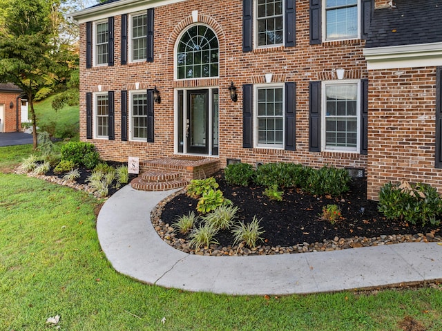 entrance to property with a yard and brick siding