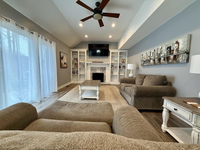 living room with a ceiling fan, wood finished floors, recessed lighting, a fireplace with raised hearth, and vaulted ceiling