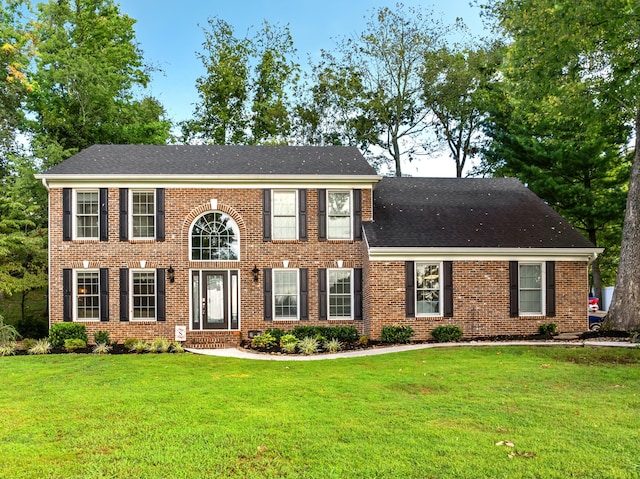 colonial inspired home with a front lawn, brick siding, and roof with shingles