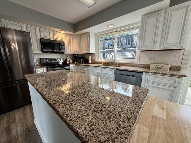 kitchen featuring a sink, dark stone counters, backsplash, and stainless steel appliances