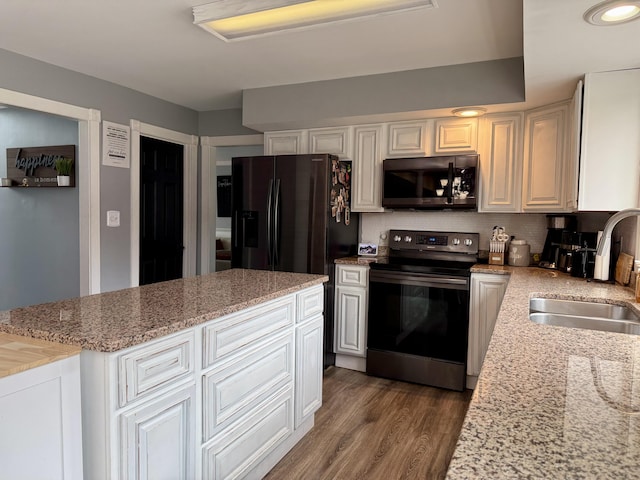 kitchen featuring wood finished floors, a sink, black fridge with ice dispenser, range with electric stovetop, and backsplash