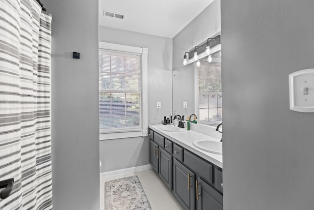 bathroom with tile patterned floors, visible vents, double vanity, and a sink