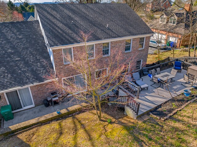 back of house featuring brick siding, a wooden deck, and a shingled roof