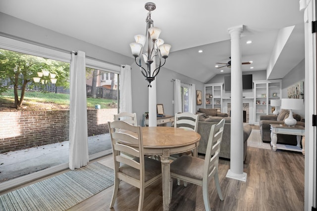 dining space with ceiling fan with notable chandelier, wood finished floors, decorative columns, and a fireplace