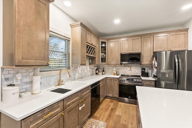 kitchen with decorative backsplash, light hardwood / wood-style floors, sink, and appliances with stainless steel finishes