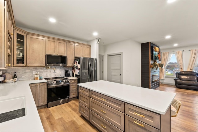 kitchen featuring decorative backsplash, a center island, light hardwood / wood-style floors, and appliances with stainless steel finishes