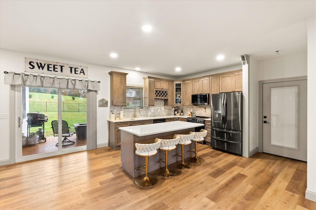 kitchen featuring a center island, sink, stainless steel appliances, a kitchen breakfast bar, and light hardwood / wood-style floors