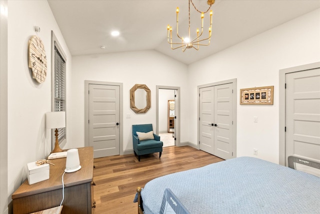 bedroom featuring hardwood / wood-style flooring, lofted ceiling, and a notable chandelier