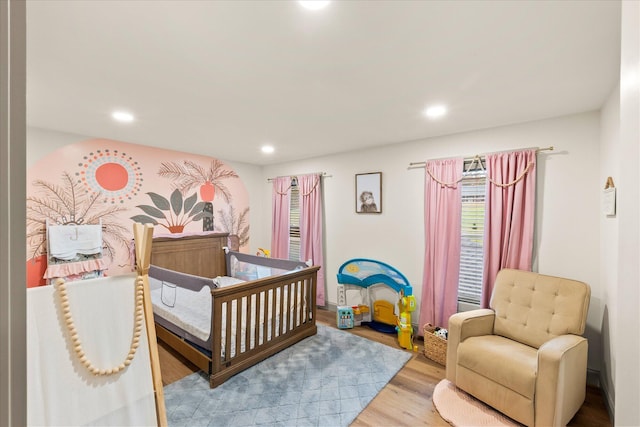 bedroom featuring wood-type flooring and a nursery area