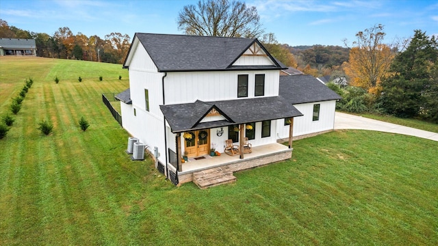 view of front of house with central AC, covered porch, and a front yard