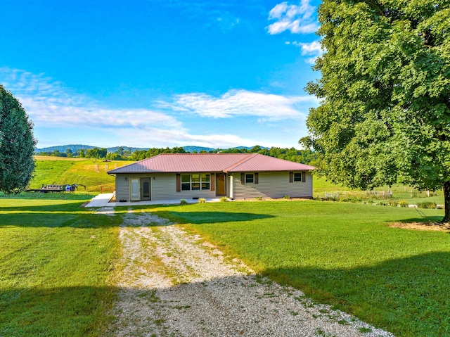 view of front of property featuring a front yard, driveway, a patio area, and metal roof