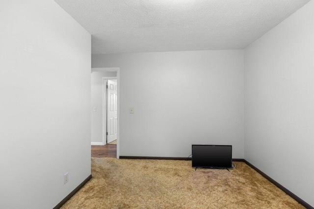 spare room featuring baseboards, carpet flooring, and a textured ceiling