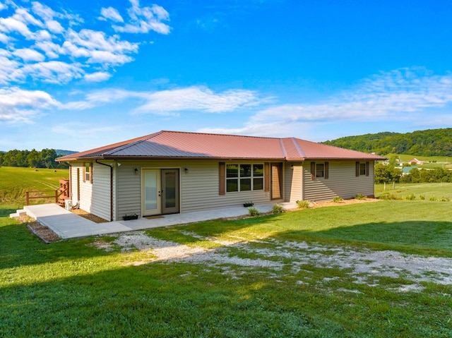 back of property featuring metal roof and a yard