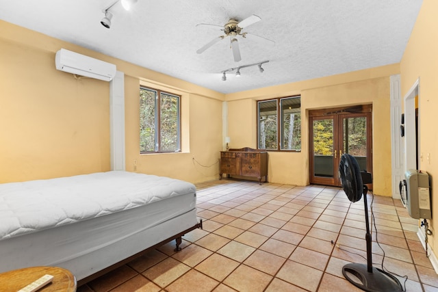 tiled bedroom featuring a textured ceiling, multiple windows, ceiling fan, and a wall mounted air conditioner