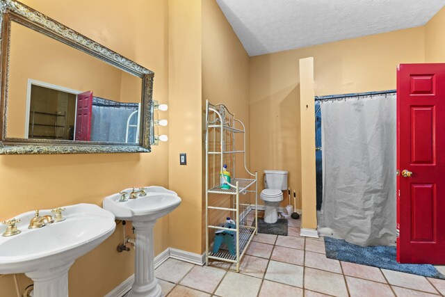 bathroom featuring a shower with curtain, a textured ceiling, sink, tile patterned flooring, and toilet