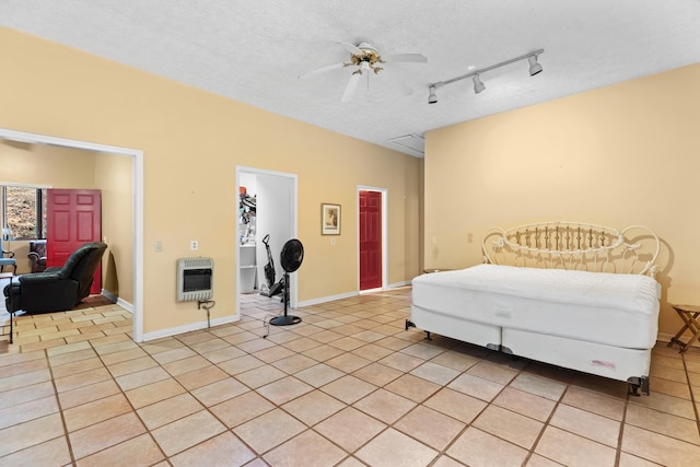 bedroom with ceiling fan, light tile patterned flooring, a spacious closet, and heating unit