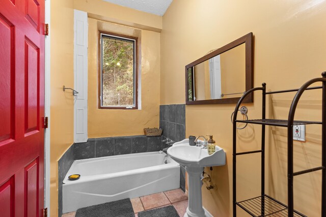 bathroom with tile patterned flooring, a bath, and a textured ceiling