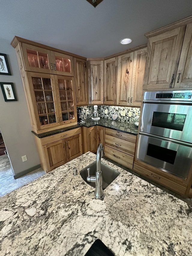 3041 Wineberry Ln, Morristown, TN 37814 - kitchen featuring a sink, double oven, light stone countertops, glass insert cabinets, and tasteful backsplash