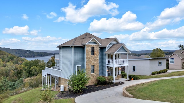 view of front facade featuring a balcony, a water view, and a front yard