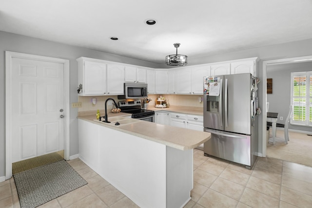 kitchen with light countertops, a sink, a peninsula, stainless steel appliances, and white cabinetry