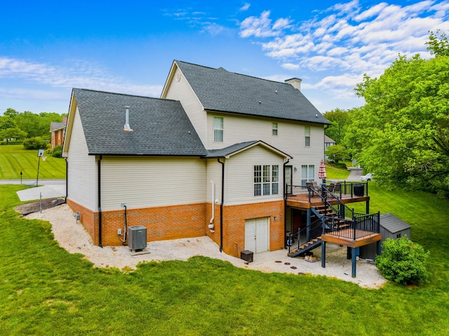 back of house featuring stairway, a deck, a yard, and brick siding