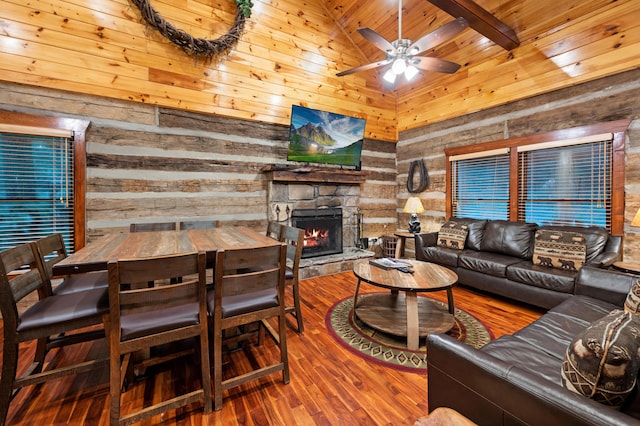 living room with a stone fireplace, beamed ceiling, wooden walls, high vaulted ceiling, and wooden ceiling