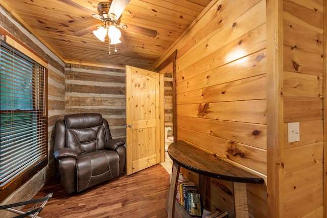 sitting room featuring hardwood / wood-style flooring, ceiling fan, wooden walls, and wooden ceiling