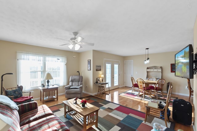 living room with ceiling fan, light wood-type flooring, and french doors