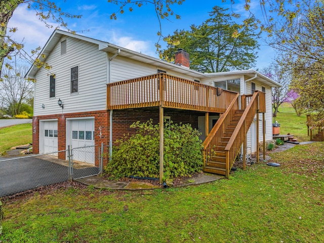 view of side of property with stairway, a chimney, an attached garage, aphalt driveway, and a yard