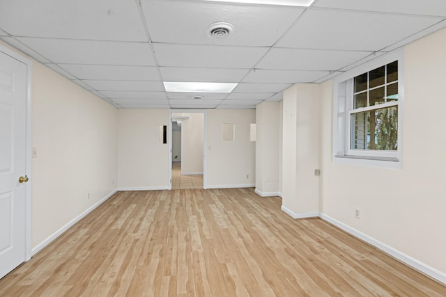 finished below grade area featuring baseboards, visible vents, a paneled ceiling, and light wood-type flooring