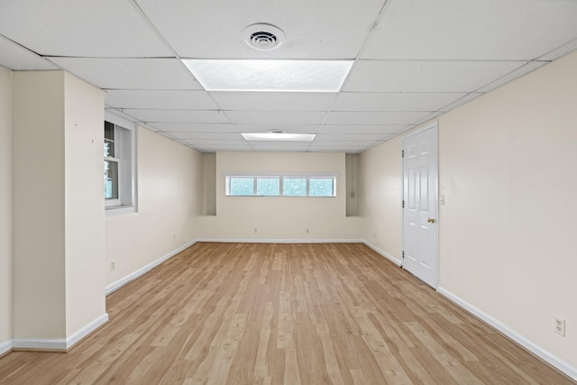 empty room with a paneled ceiling, baseboards, light wood finished floors, and visible vents