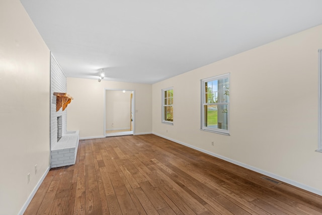 unfurnished living room featuring baseboards, a fireplace, visible vents, and hardwood / wood-style floors
