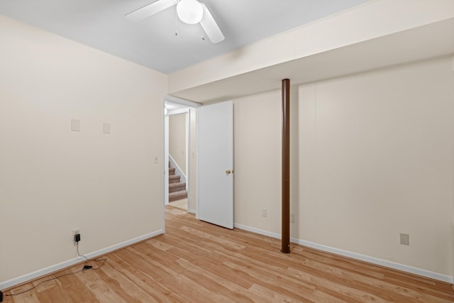 finished below grade area featuring baseboards, stairs, ceiling fan, and light wood-type flooring