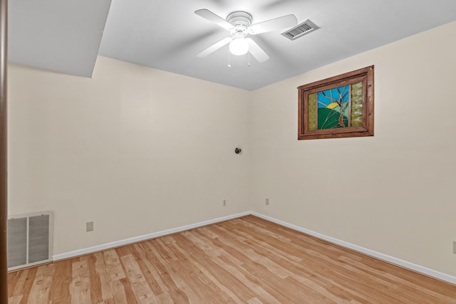 spare room with light wood-type flooring, a ceiling fan, baseboards, and visible vents