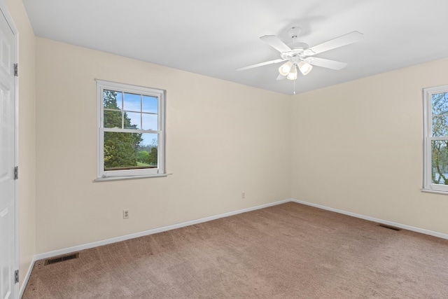 carpeted empty room with baseboards, visible vents, and a ceiling fan