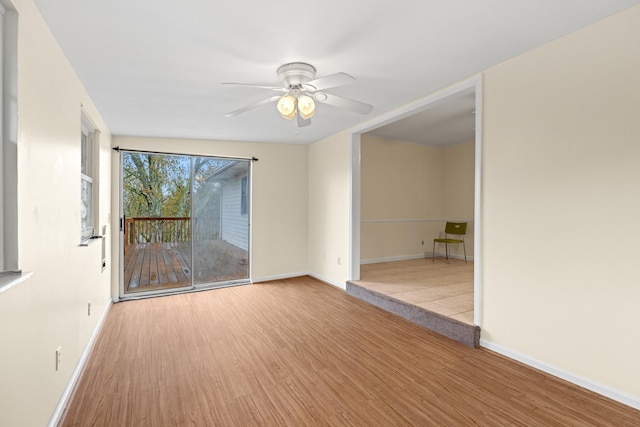 spare room with baseboards, wood finished floors, and a ceiling fan