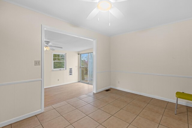 spare room with light tile patterned floors, a wainscoted wall, visible vents, and a ceiling fan