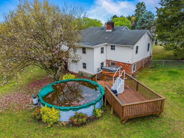 rear view of house with a chimney, fence, a wooden deck, and a yard