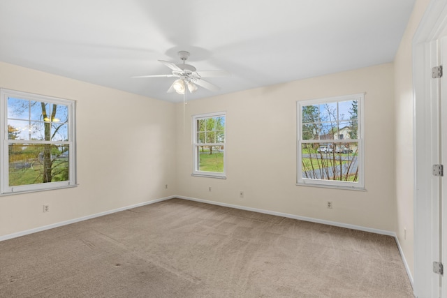 empty room with baseboards, ceiling fan, and light colored carpet
