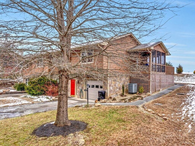 view of front of house with a garage, central AC, and a sunroom