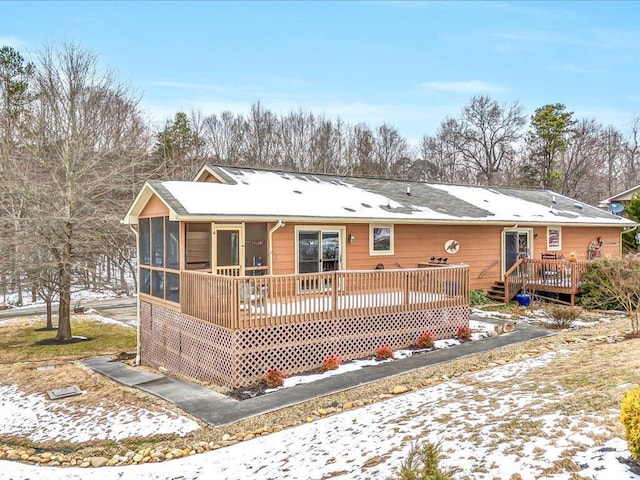 snow covered property featuring a deck and a sunroom