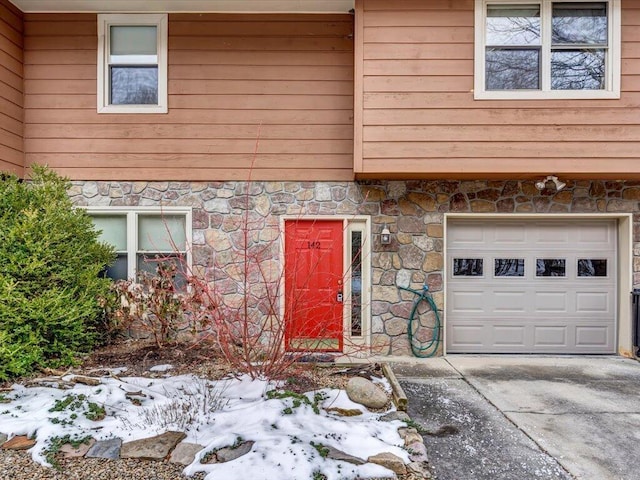 snow covered property entrance featuring a garage