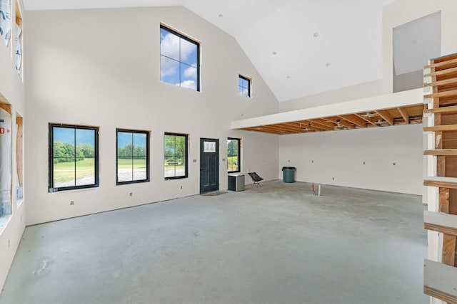 unfurnished living room featuring concrete floors and a high ceiling