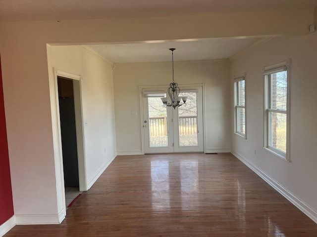 unfurnished dining area with ornamental molding, baseboards, an inviting chandelier, and wood finished floors