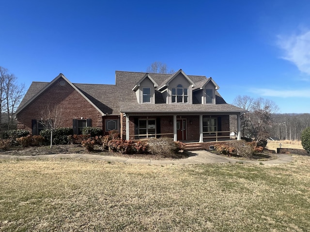 view of front of home with brick siding, a porch, and a front lawn