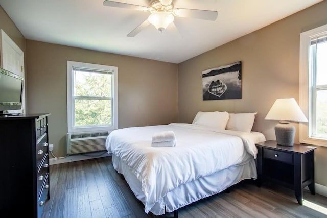 bedroom with multiple windows, dark hardwood / wood-style floors, and a wall mounted air conditioner