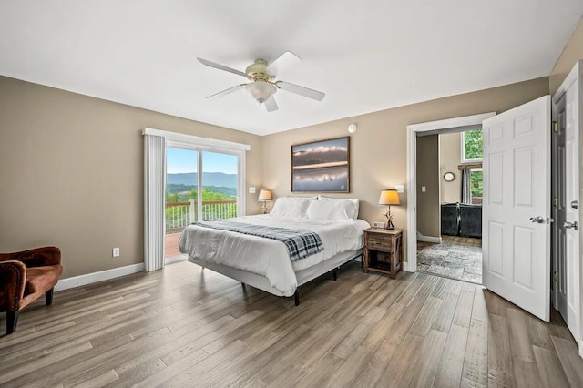 bedroom with a mountain view, access to exterior, ceiling fan, and light hardwood / wood-style flooring