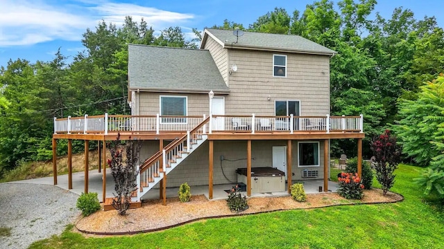 back of property with a wooden deck, a hot tub, a patio area, and a lawn