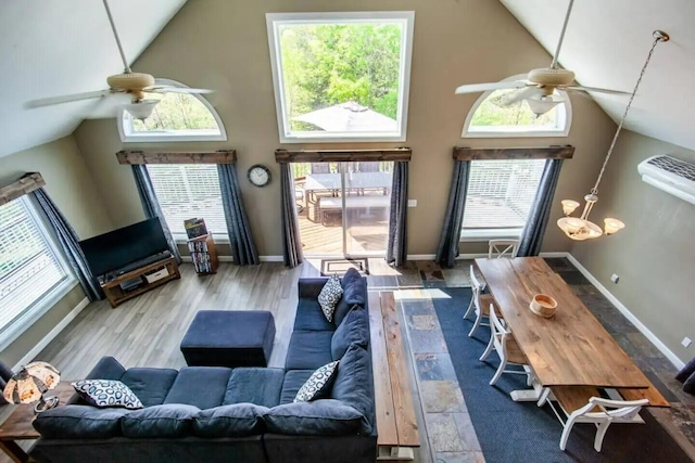 living room with ceiling fan with notable chandelier, high vaulted ceiling, and a healthy amount of sunlight