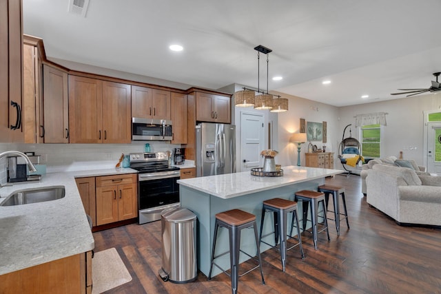 kitchen with appliances with stainless steel finishes, a sink, a kitchen breakfast bar, open floor plan, and a center island